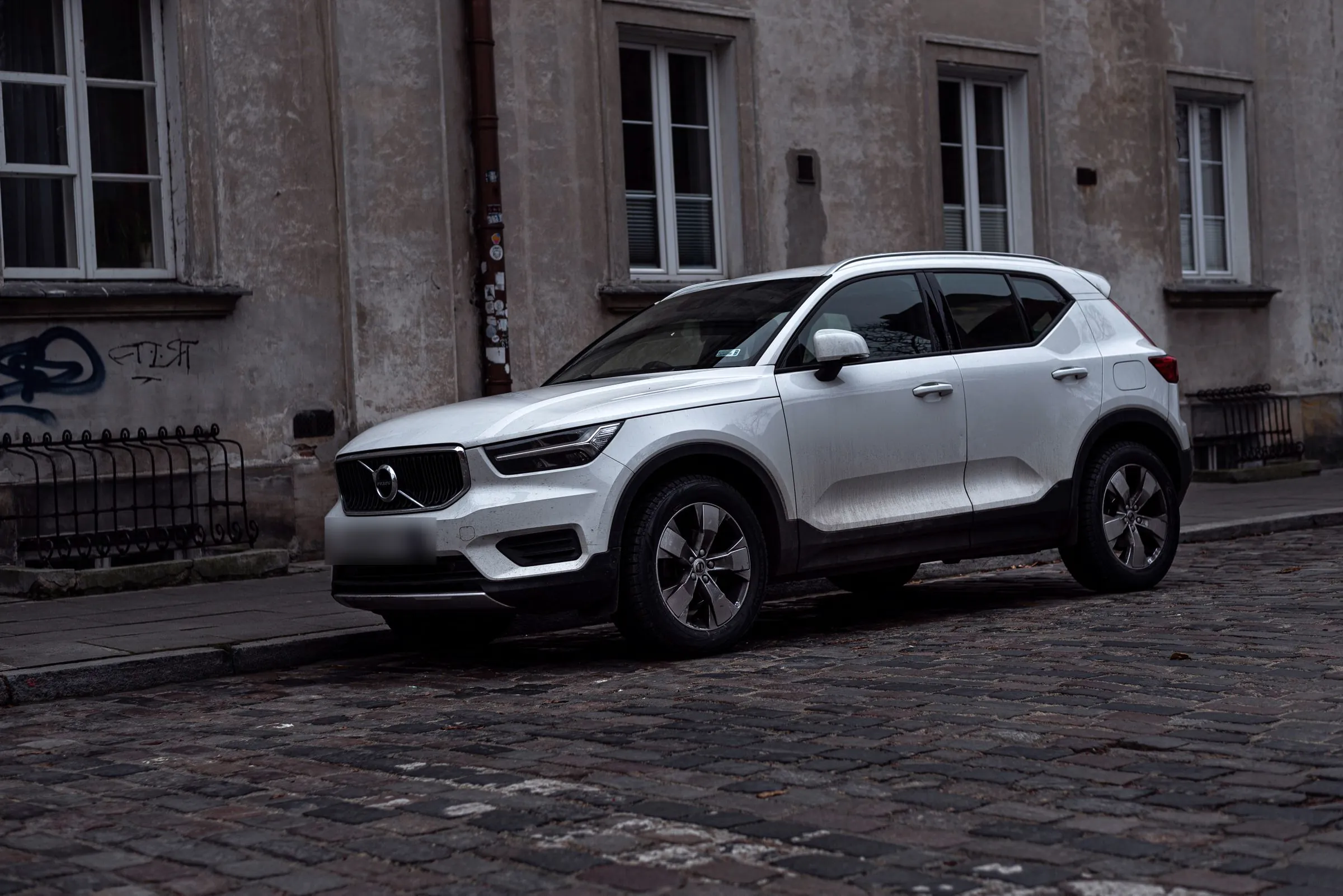 En vit Volvo parkerad på en europeisk kullerstensgata i dagsljus